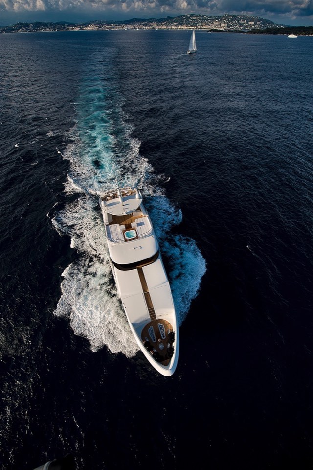 Top-down drone view of a superyacht carving a white wake