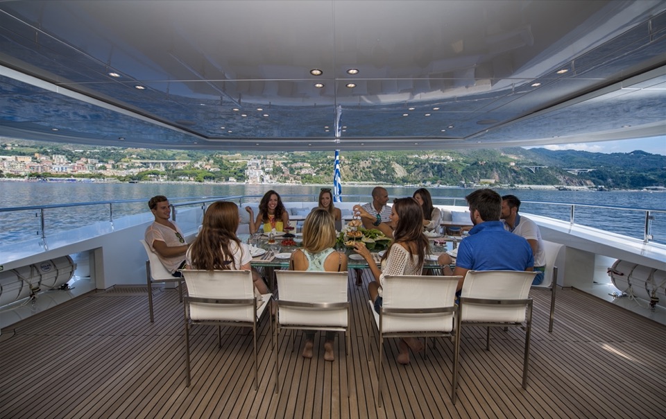 Guests at lunch at the deck table, the coast behind