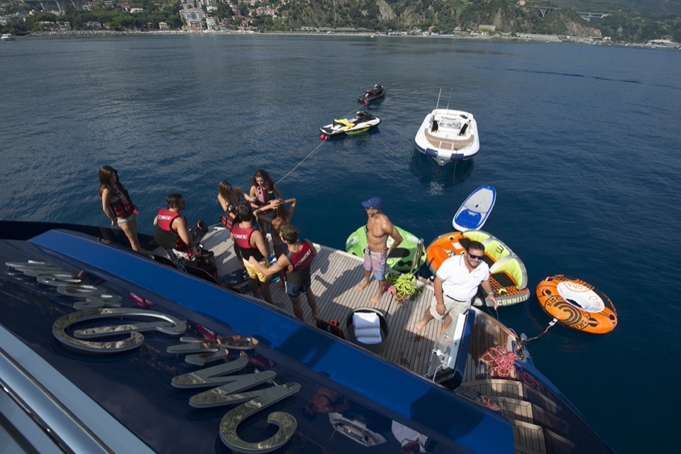 Aerial of guests on the swim platform, with toys and a tender in the water