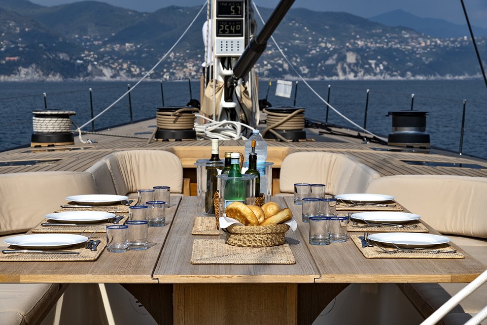 Table laid for lunch on the deck of a sailing yacht, coastline behind