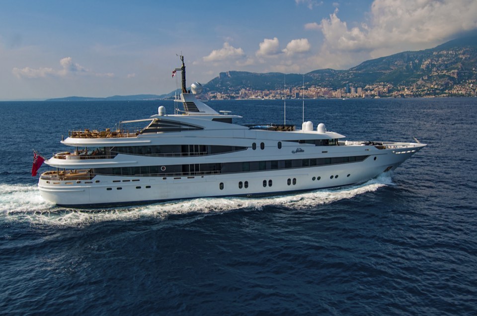 Superyacht running along a mountainous coastline