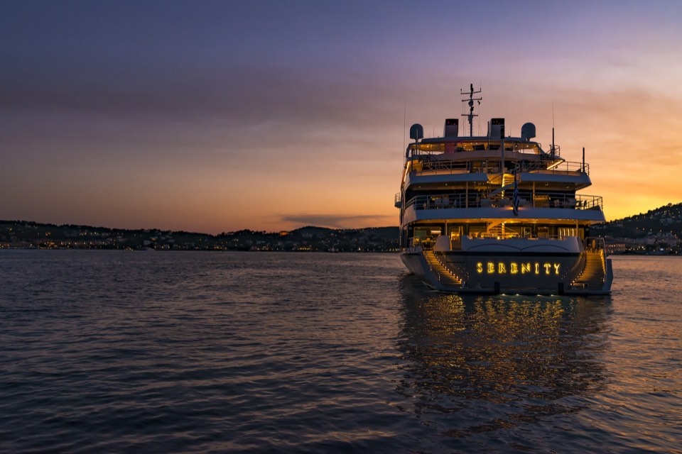 M/Y Serenity (86 m) at anchor at sunset, her name lit on the transom