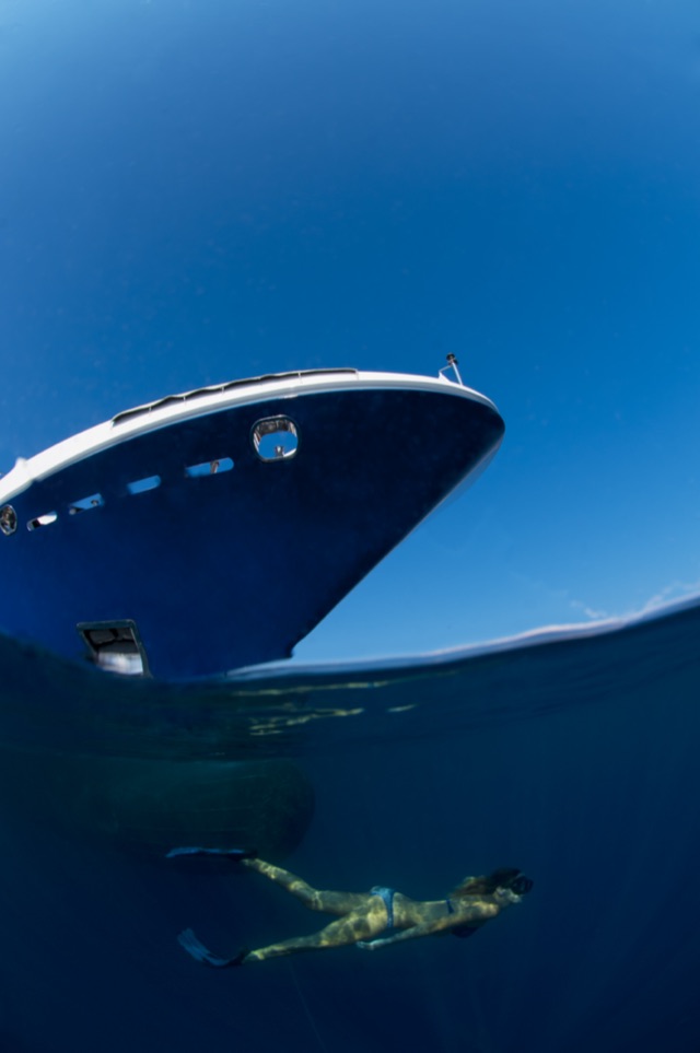 Bow of M/Y My Dream above the surface and a swimmer below, split-level view